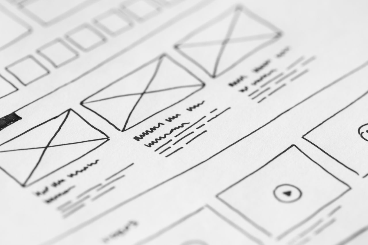 heros-img Detailed close-up of a hand-drawn wireframe design on paper for a UX project.